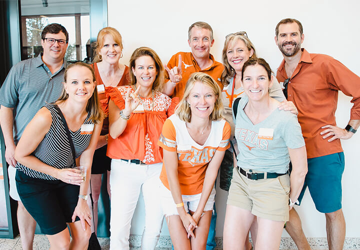 Group of smiling alumni wearing University of Texas gear