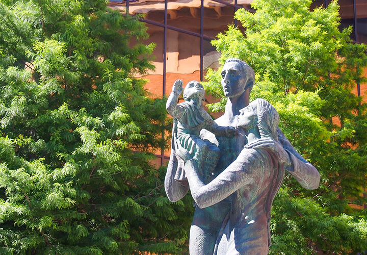 McCombs family statue in front of green trees