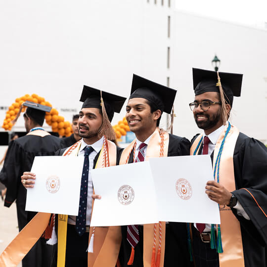 Three BBA graduates pose with diplomas