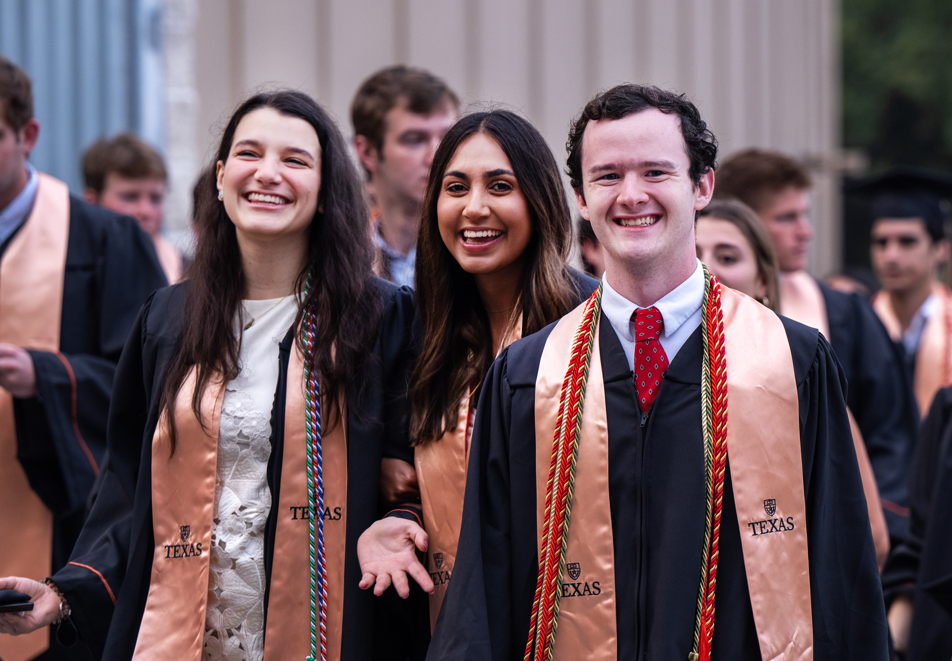 A group of three students smiling in their graduation gowns.