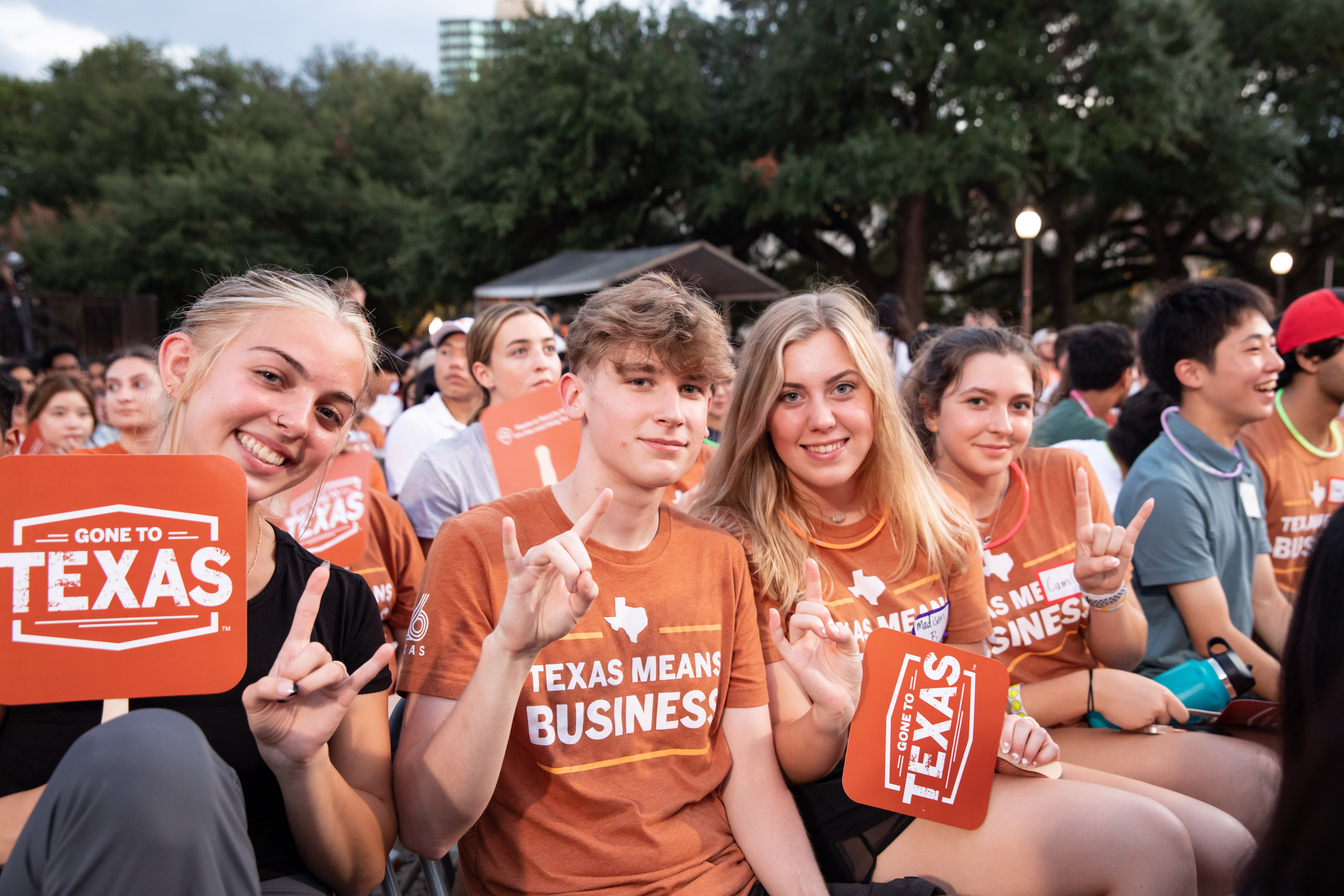 Students in orange, Texas Means Business, shirts sitting together.