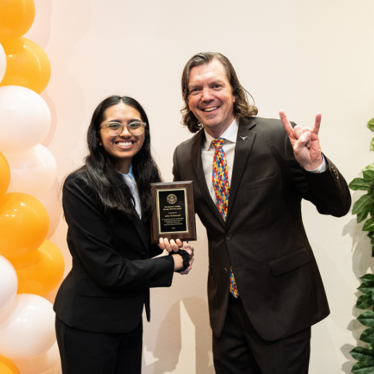 A student shakes the undergraduate dean's hand as they receive the Barbara Jordan and George Mitchell award.