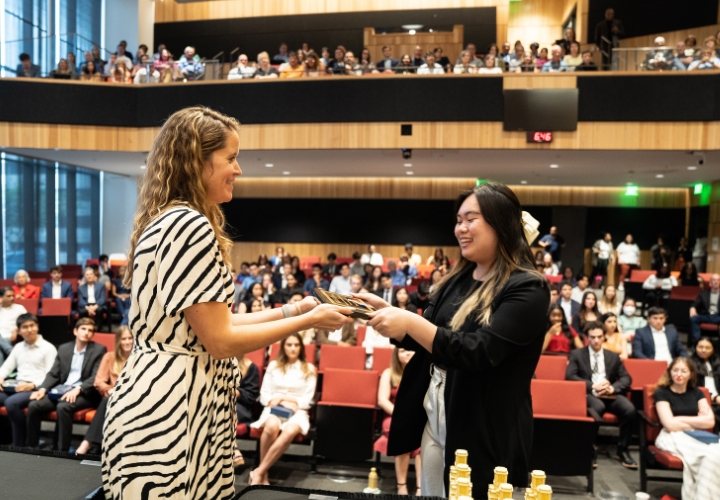 A student receives an award in front of a crowd.