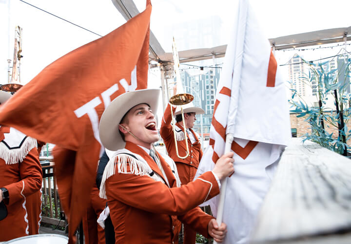 University of Texas band member cheering and holding flag